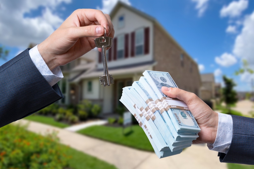 Man handing another man a stack of cash in exchange for house keys