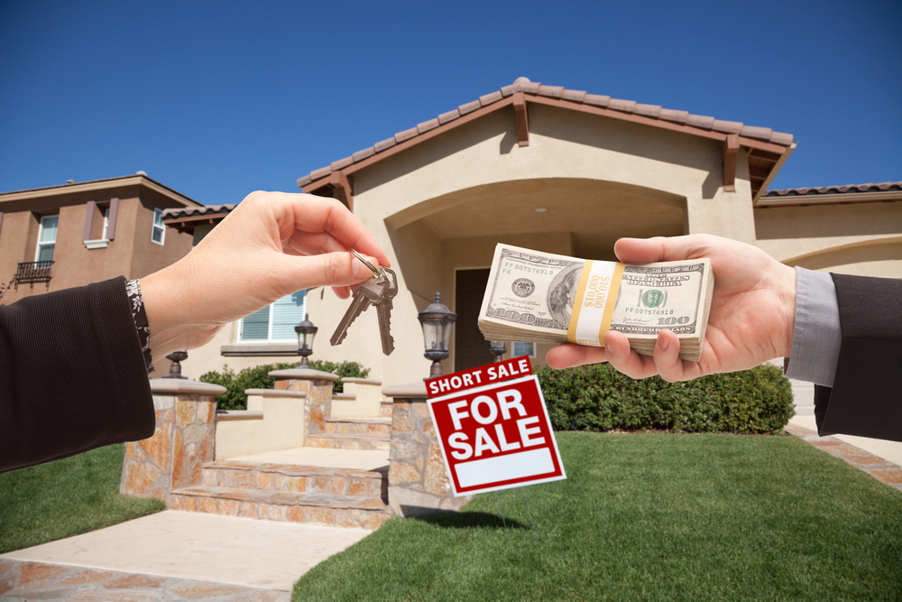 Handing Over Cash For House Keys and Short Sale Real Estate Sign in Front of Home.