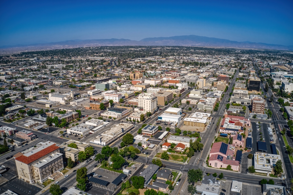 Aerial view showcasing the expansive skyline of downtown Bakersfield, California, with distinctive buildings, streets, and natural scenery in the background.